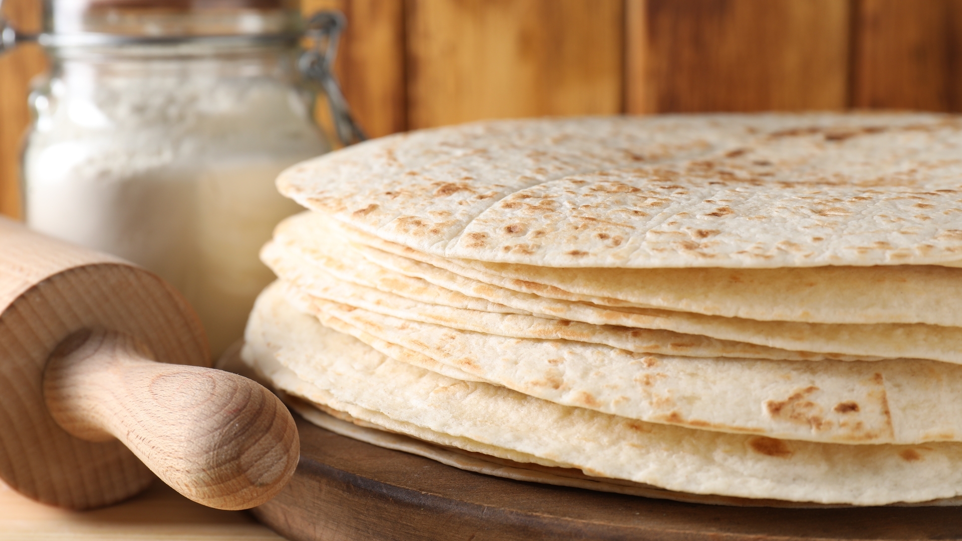Many tasty homemade tortillas on wooden table, closeup